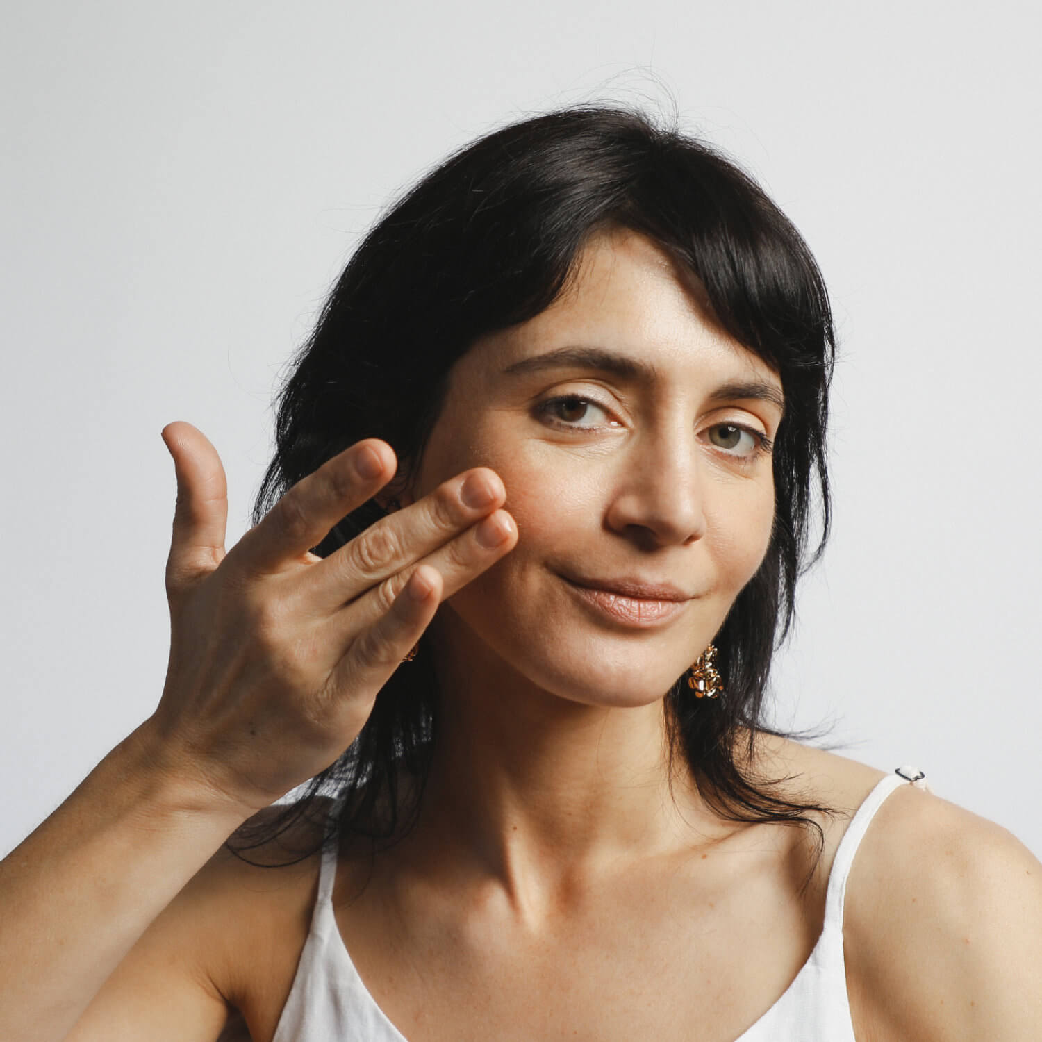 Model is applying 24K-Gold-face-oil by Mohi Skin Care to her cheeks.