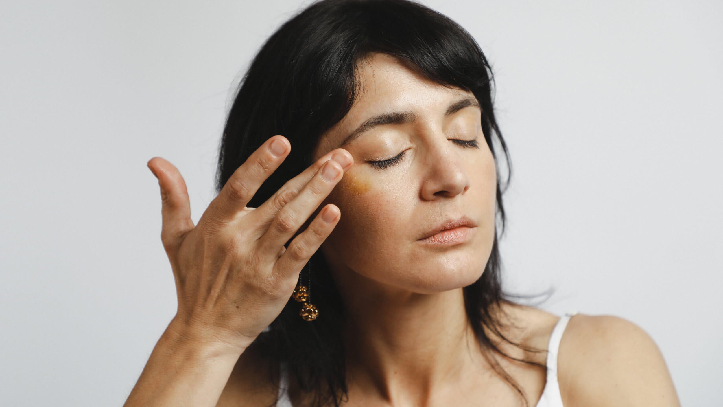 Model is applying 24K-Gold-face-oil by Mohi Skin Care to her face