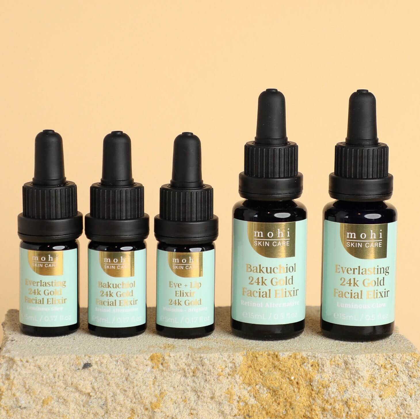 The Mohi Skin Care 24k gold facial oil range lined up on a brick.